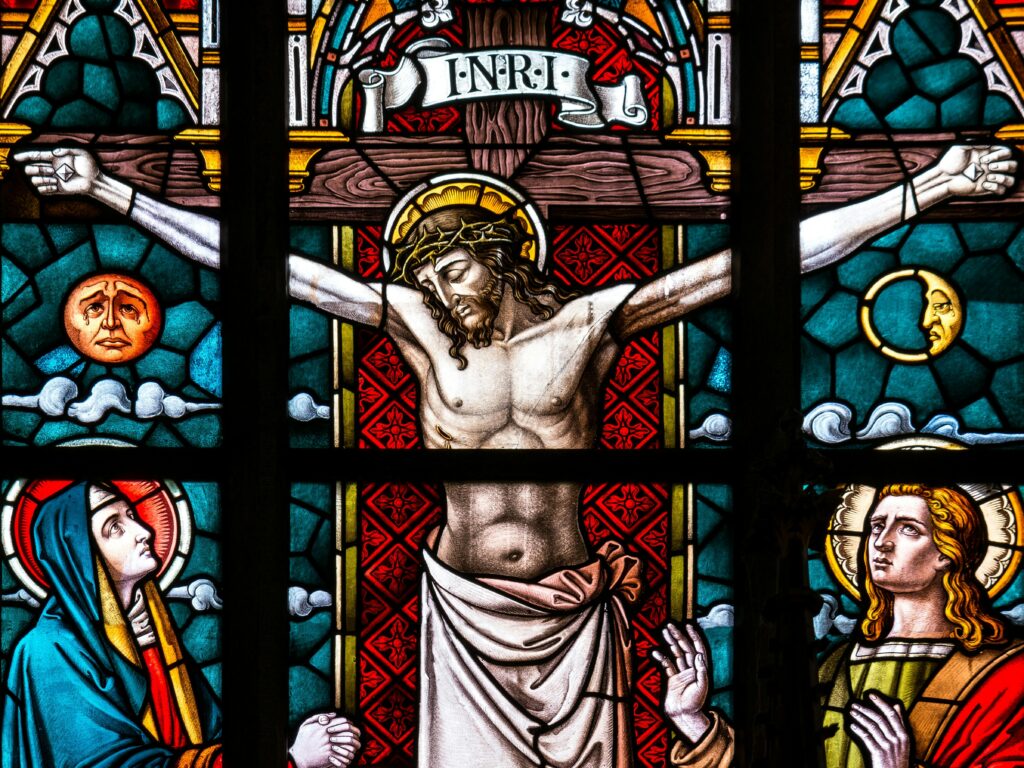 Detailed stained glass depiction of the crucifixion featuring Christ and religious icons.